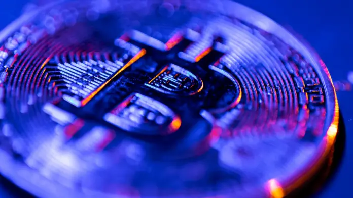 Κοντινή λήψη νομίσματος Bitcoin με μπλε φωτισμό, ως συμβολική εικόνα για την άνοδο της τιμής μετά το halving 2024–2025.