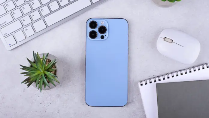 Smartphone με τριπλή κάμερα πάνω σε γραφείο, δίπλα σε πληκτρολόγιο και σημειωματάριο, ως εικόνα για φωτογραφίες με iPhone και mobile photography tips.