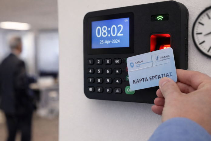 Χέρι σκανάρει κάρτα εργασίας σε ψηφιακό ρολόι παρουσίας, δείχνοντας καταγραφή ώρας προσέλευσης και αποχώρησης