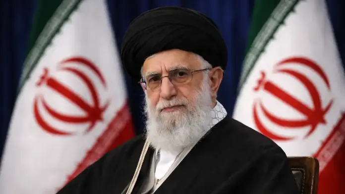 Institutional, text-free featured image for reporting on Iran’s leadership claims: a formal portrait-style scene of Iran’s supreme leader with softly blurred Iranian flags in the background, composed with safe margins for 16:9 cropping.