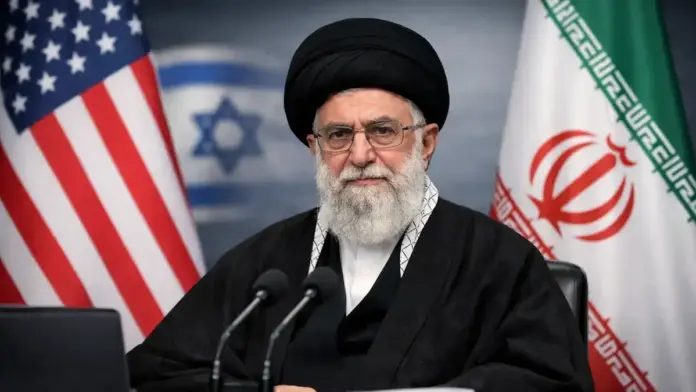 Institutional geopolitical image showing Iran’s leadership between the United States and Iran flags, with a blurred Israeli flag in the background