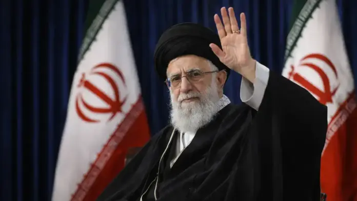 Θεσμική επιλεγμένη εικόνα για ρεπορτάζ σχετικά με συγκρουόμενες αναφορές για τον Αλί Χαμενεΐ: πορτρέτο θρησκευτικού ηγέτη με ιρανικές σημαίες στο φόντο, κάδρο ασφαλές για περικοπή 16:9.