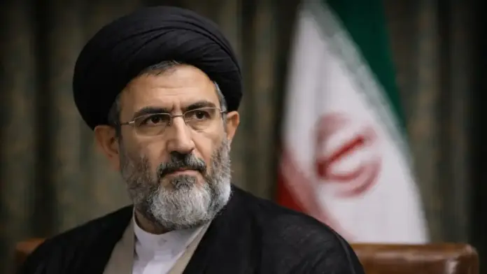 Θεσμικό πορτρέτο του Μοτζτάμπα Χαμενεΐ με φόντο ιρανική σημαία