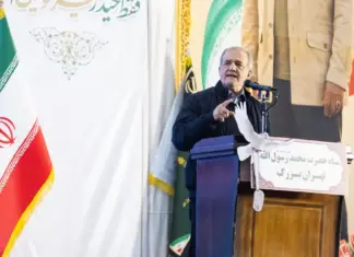 Ο Μασούντ Πεζεσκιάν μιλά σε βήμα δίπλα στην ιρανική σημαία κατά τη διάρκεια δημόσιας ομιλίας στην Τεχεράνη